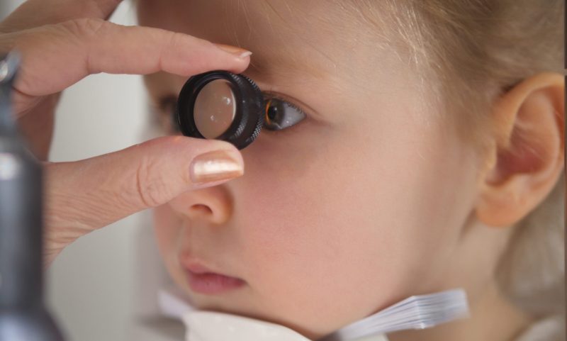Child in ophthalmology clinic - optometrist diagnosis little blonde girl, close up