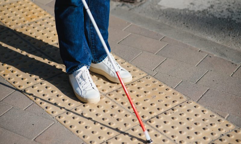 Close-up Of A Blind Man Standing With White Stick On Street.