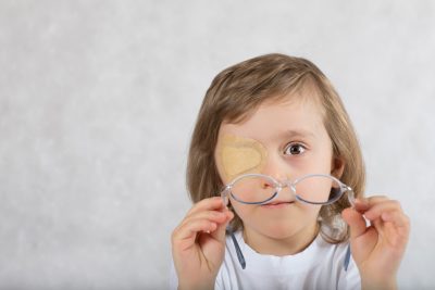 Five years old boy with one eye covered by eye pad and with eye glasses.