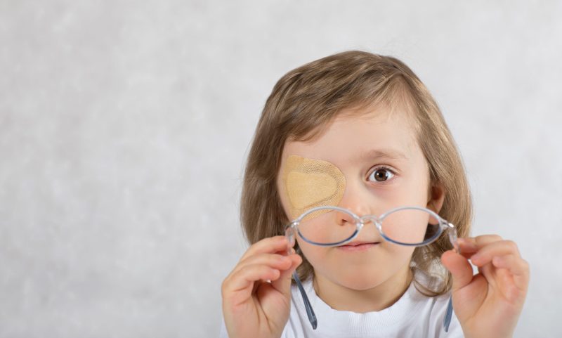 Five years old boy with one eye covered by eye pad and with eye glasses.