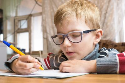 Focused first grader learning to write and doing homework.