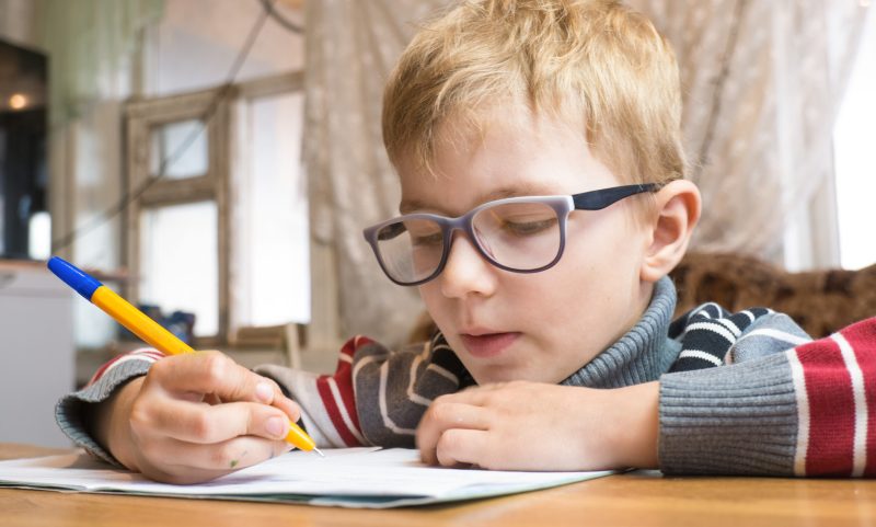 Focused first grader learning to write and doing homework.